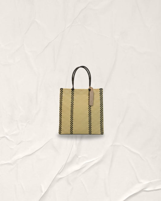 Hand-woven Pilar Bag in Serene Cream with two vertical Anchor Black lines on each side. Medium-sized tote with cream handles, crafted from recycled plastic. This sustainable Indonesian bag features a vertical architectural design and is washable and foldable